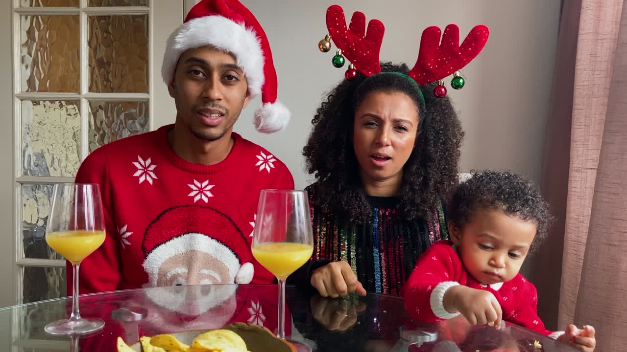 padres jóvenes con un niño pequeño en una videollamada navideña tratando de adivinar la palabra actuada durante el juego de charadas