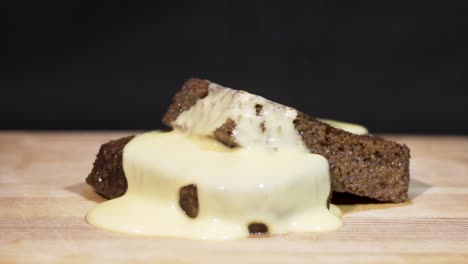 close up shot of custard running off malva pudding with a black background