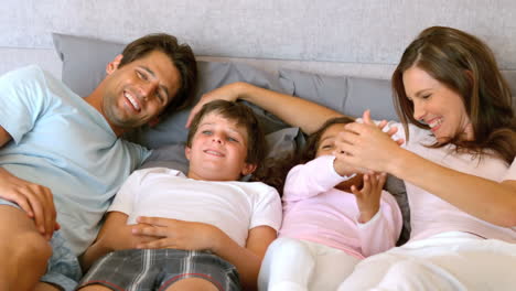 Familia-Feliz-Acostada-En-Una-Cama