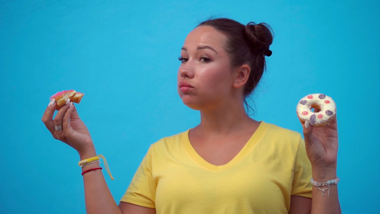 Jovem Mulher Comendo um Donut Glaceado Contra um Fundo Azul