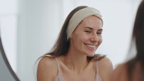 white teeth woman smiling in bathroom mirror. closeup happy lady enjoying smile