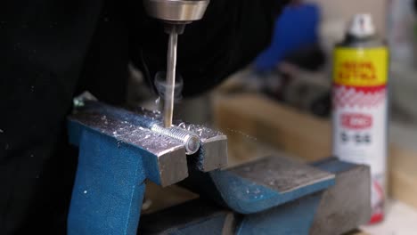 medium shoot of professional craftsman drilling a hole in stainless steel