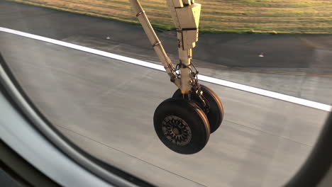 airplane passenger view of wheels touching down on tarmac as airplane lands