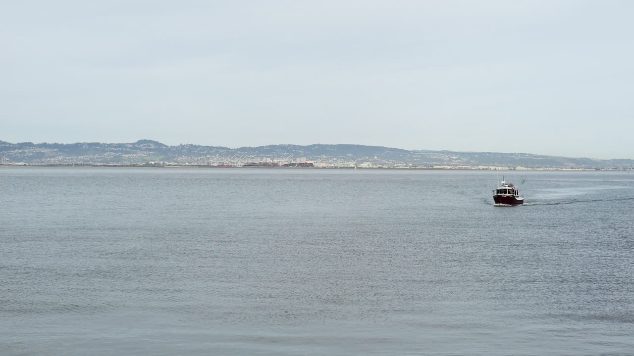 남미 해안 지역의 평온한 바다를 항해하는 작은 밀매 어선, 카메라는 거대한 다리를 향해 파노라마 움직임을 만 ⁇ 니다, 남미