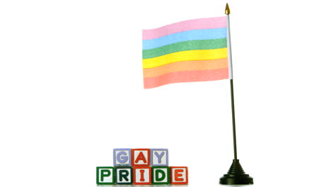 bandera del arco iris soplando en el viento al lado de bloques de orgullo gay en fondo blanco