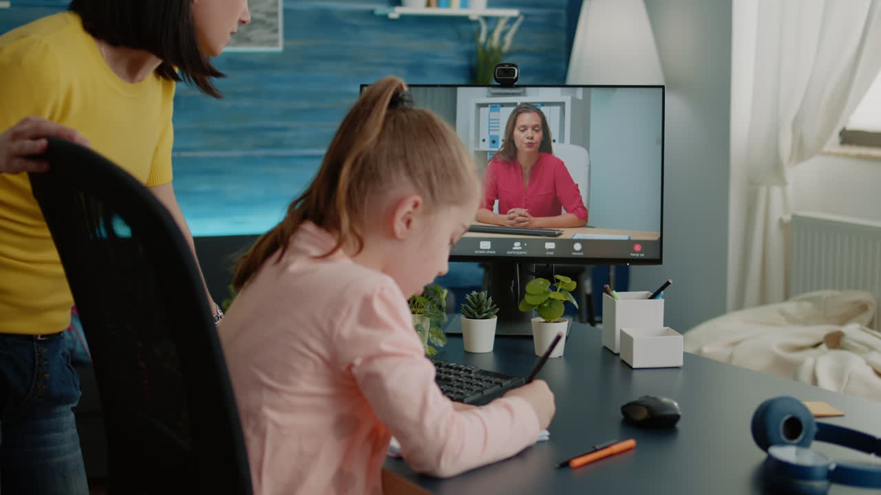 Pupil writing on notebook with teacher on video call