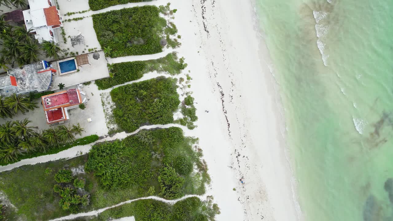 Beachfront aerial view with tropical villas, sandy paths, and turquoise waters in Cuyo, Mexico