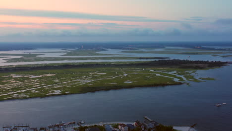 slow-pan-left-at-sunset,-viewing-a-pink-painted-sky,-as-the-drone-moves,-the-view-feels-like-a-plane-landing-at-Point-Lookout,-New-York