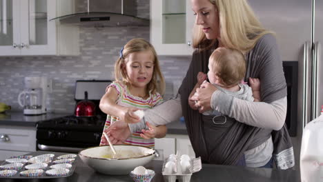 young girl preparing cake mix mix in kitchen, mum showing baby, shot on r3d