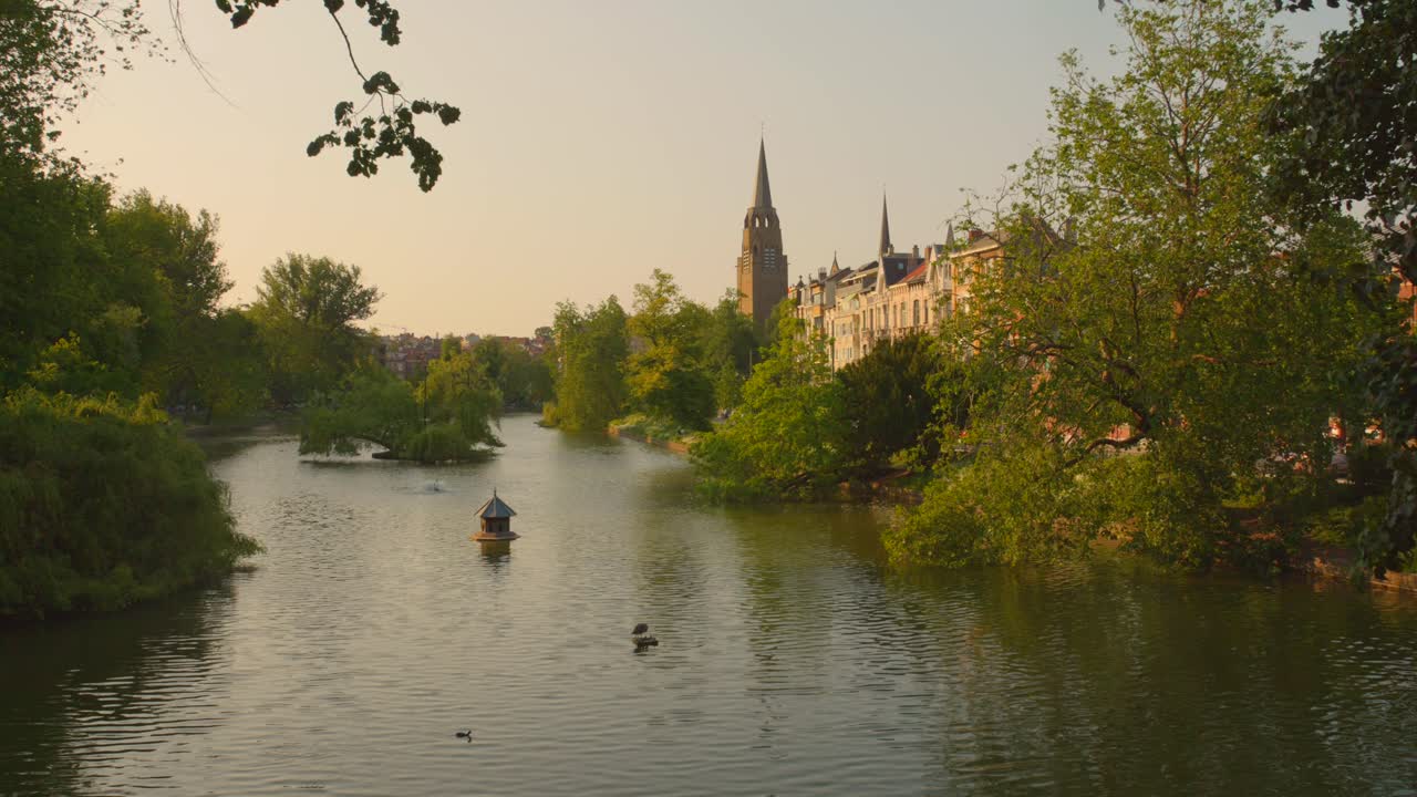 toma de ángulo alto sobre los estanques de ixelles en bruselas, bélgica con una vieja iglesia en el fondo en la hora dorada
