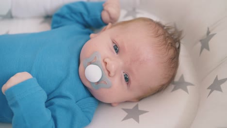 un bebé recién nacido feliz chupa a un muñeco en un capullo en una cuna mecedora