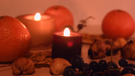 Primer-Plano-De-Un-Fondo-Otoñal-Con-Hojas,-Mandarina,-Castañas,-Velas-Y-Uvas