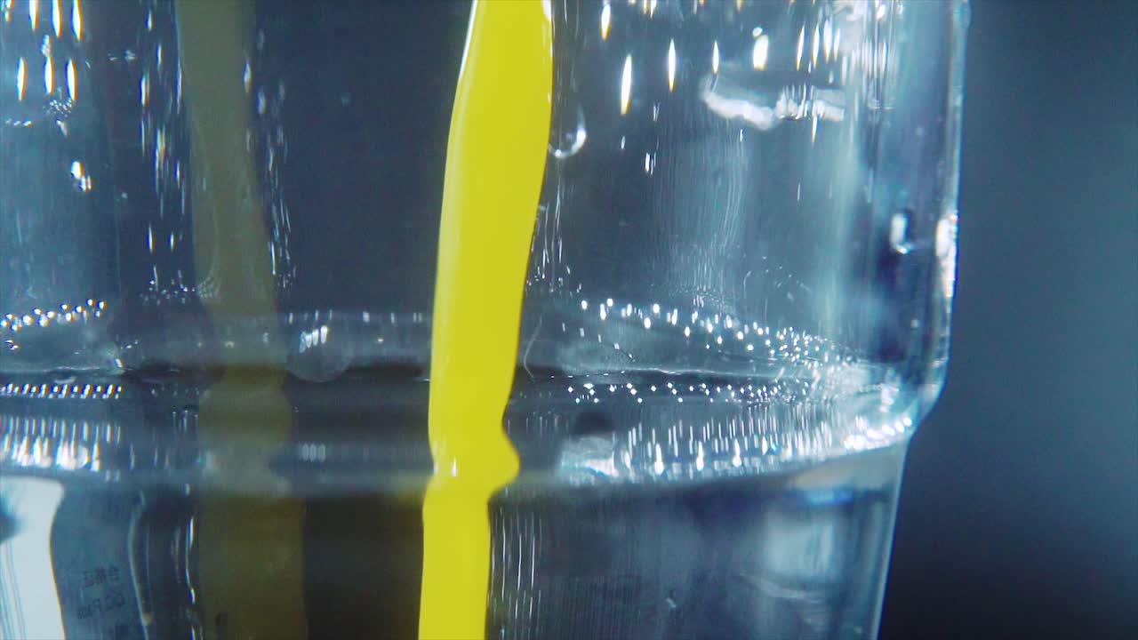 A macro close up shot of a glass filled with fresh squeezed orange juice, slow motion, studio light, 4K video