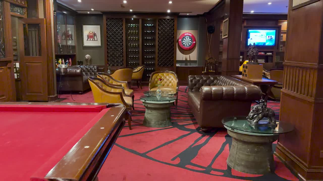 Elegant hotel bar with red pool table, leather seating, warm lighting, and smooth camera pan
