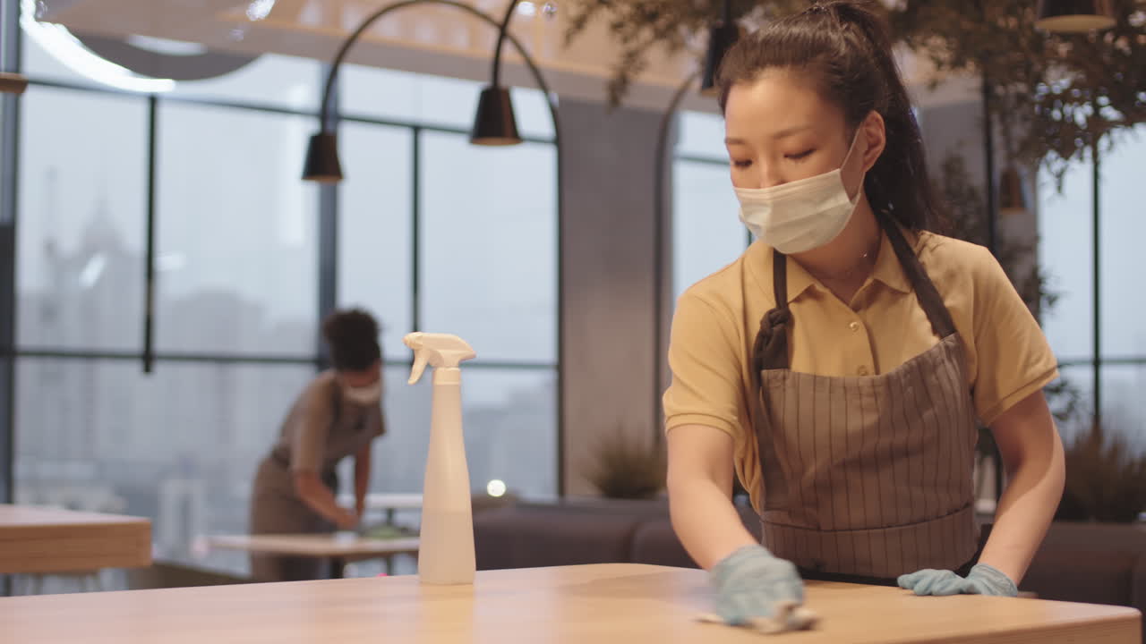 Asian Female Cafe Worker Disinfecting Table