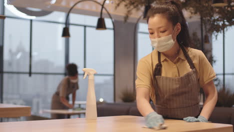 asian female cafe worker disinfecting table