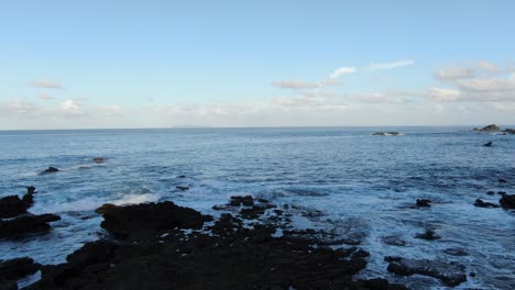 Vista-De-Drones-En-La-Playa-De-Costa-Rica-Volando-Hacia-El-Océano-Proveniente-De-Una-Zona-Rocosa-A-La-Sombra-Temprano-En-La-Mañana-En-El-Océano-Pacífico-En-Un-Día-Soleado