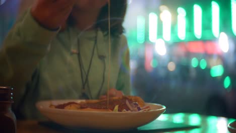 girl eating cheesy pasta in cafe restaurant at night.