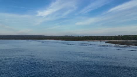 Rising-drone-clip-over-open-ocean-showing-remote-island-tip-of-Java,-Indonesia-with-calm-waters