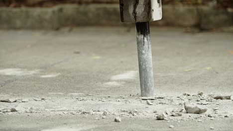 close-up of excavator hydraulic arm rock breaker working on concrete road with sound