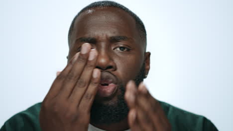 closeup african man throwing air kiss from hand in grey background in studio.