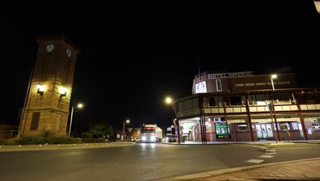 trucks and cars pass by an old building at night