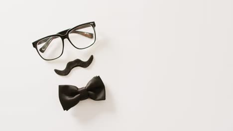 video de bigote falso negro, gafas y pajarita sobre fondo blanco con espacio para copiar