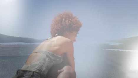 Animation-of-african-american-woman-relaxing-at-sunny-beach-over-landscape