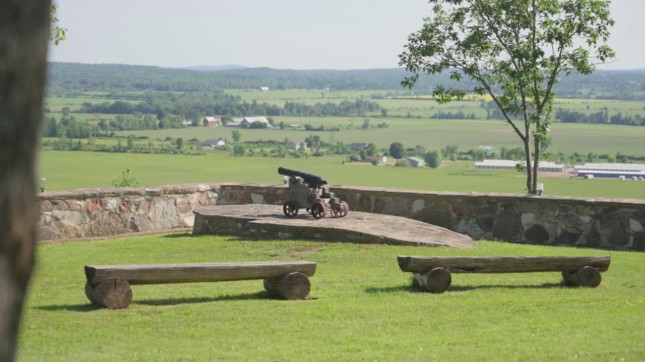 Una vista serena dai bastioni di Fort Wellington a Prescott, Ontario, con un cannone d'epoca e panchine rustiche che si affacciano sui pittoreschi campi agricoli della Valle del San Lorenzo