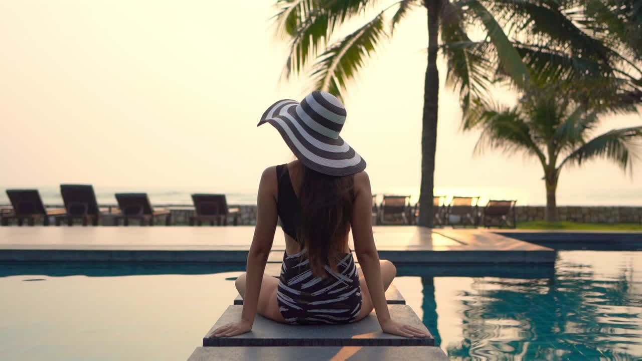 Woman in Swimwear Sitting by the Pool Enjoying Sunset. Behind, Static