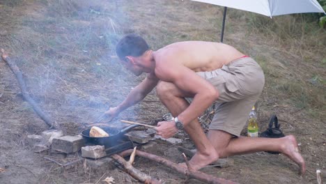 preparing meat shawarma wrapped in pita on outdoor, burning bonfire, in pan