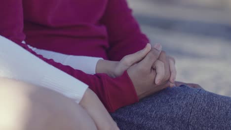 close up shot of couple holding hands outdoors in nature, symbol of togetherness and love