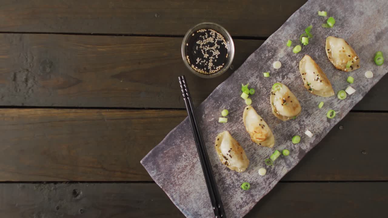 composición de plato con albóndigas de gyoza y salsa de soja con palillos sobre fondo de madera
