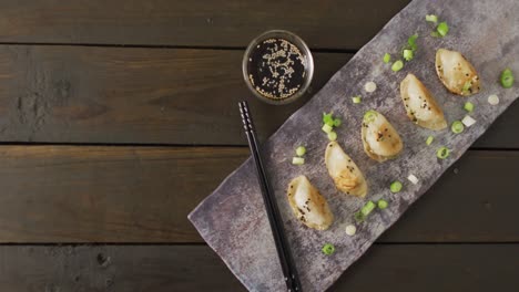 Composition-of-plate-with-gyoza-dumplings-and-soy-sauce-with-chopsticks-on-wooden-background