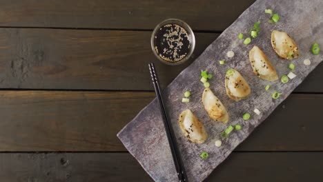 composición de plato con albóndigas de gyoza y salsa de soja con palillos sobre fondo de madera