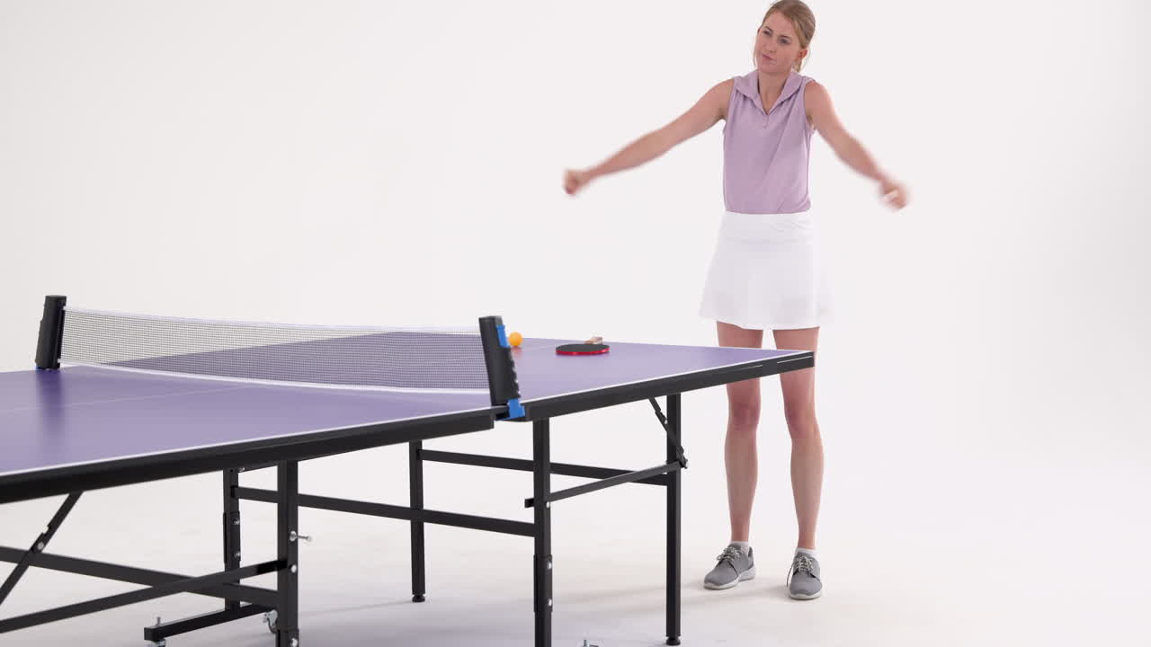 Playing table tennis, woman adjusting shirt next to table tennis table