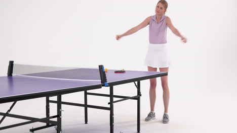 playing table tennis, woman adjusting shirt next to table tennis table