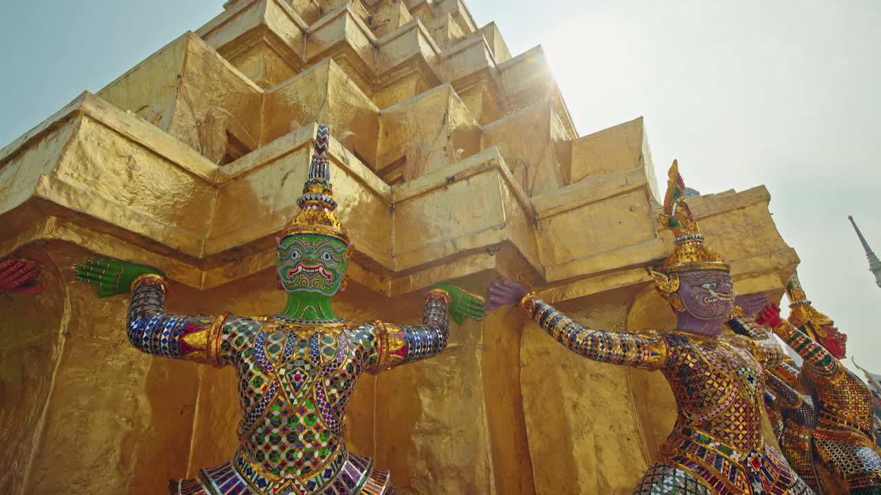Estatuas de demonios guardianes sosteniendo una estupa dorada en Wat Phra Kaew en Bangkok, colorida arquitectura de templo tailandés en Tailandia