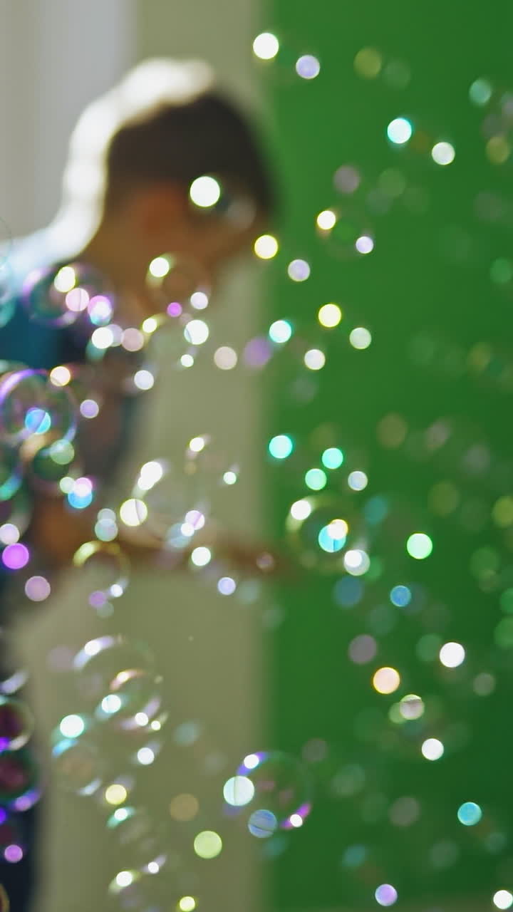 Energetic boy catching bubbles. Young child catching soap bubbles inside the room Vertical video