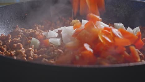 adding chopped white onion, red bell pepper, and salt into ground turkey meat cooking in pan