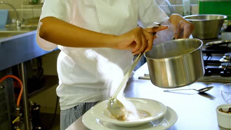 Female-chef-pouring-soup-with-ladle-into-a-plate-4k