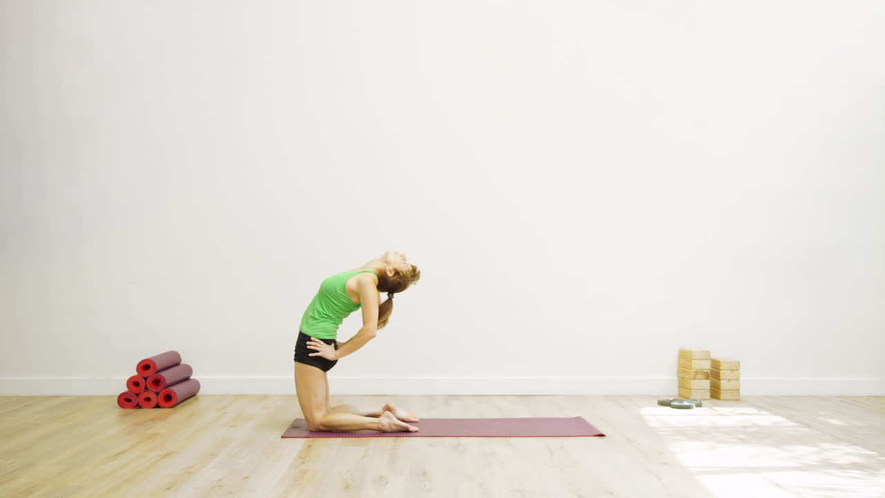 Mulher Praticando Postura do Camelo (Ustrasana) no Tapete de Yoga em Estúdio
