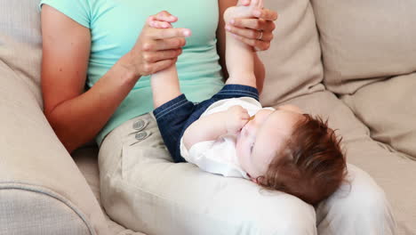 madre feliz jugando con su hijo bebé en el sofá