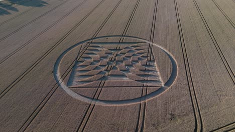 Aerial-flyover-view-above-Micheldever-Station-geometric-alien-crop-circle-artwork-tilt-up-to-harvest-farmland-countryside