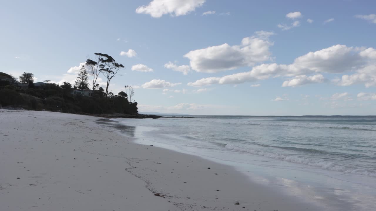 Jervis Bay Hyams Beach south of Sydney Australia calm waves on a cloudy afternoon with people walking far away, Locked shot