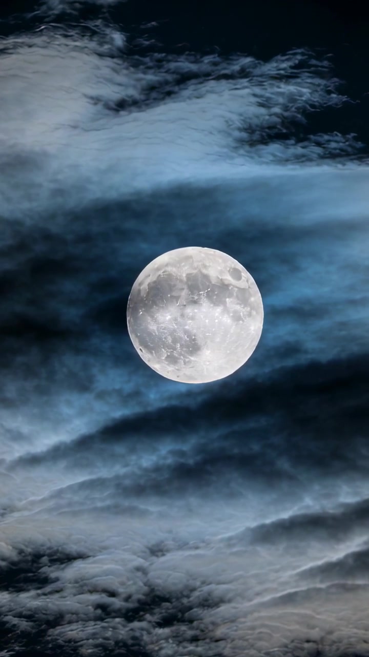 Video vertical: Capas de nubes a la deriva velando y revelando la luna llena de noche, impulsadas por el viento.