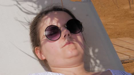 una mujer con gafas de sol descansando en una tumbona durante las vacaciones en la playa megas lakkos en kefalonia, grecia