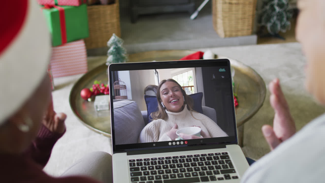 diversas amigas mayores que usan una computadora portátil para una videollamada de navidad con una mujer feliz en la pantalla