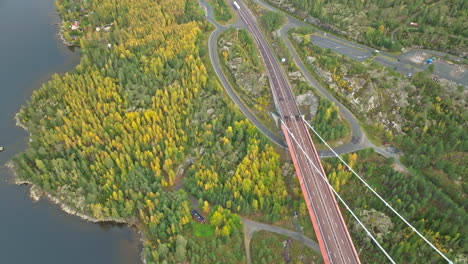 highway towards hogakustenbron bridge over autumnal woodland in sweden