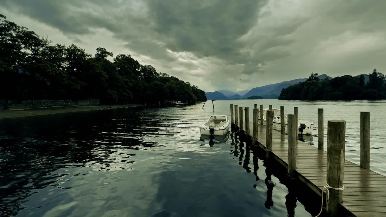어두운 하늘의 어렴풋한 구름과 잔잔한 물이 있는 부두에 정박한 두 척의 배